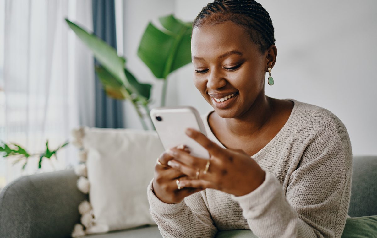 A woman smiling at her phone at home